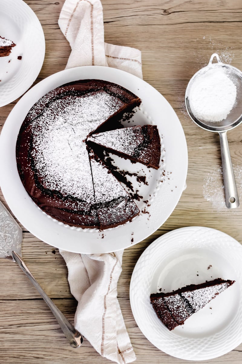overhead image of chocolate cake on a white plate with powdered sugar.