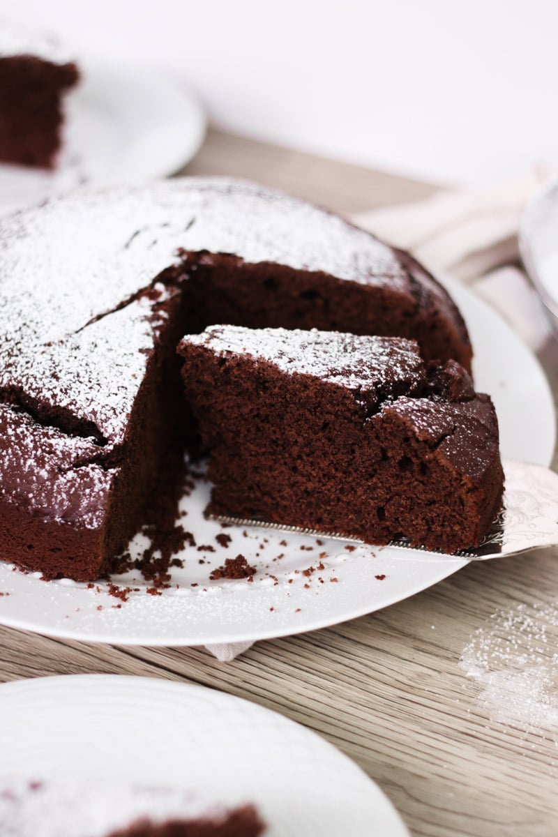 close up image of an Italian chocolate cake on a white plate being served.