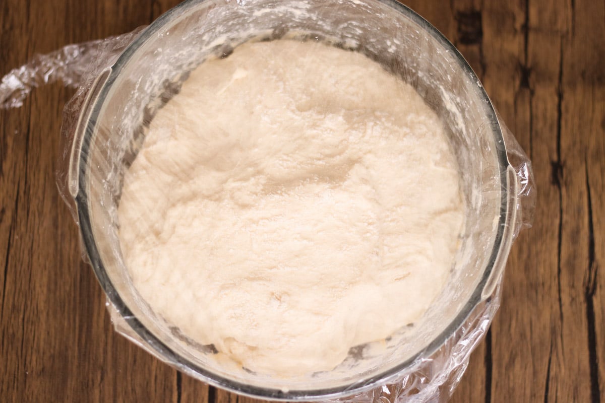 close up image of ciabatta dough in a glass bowl.