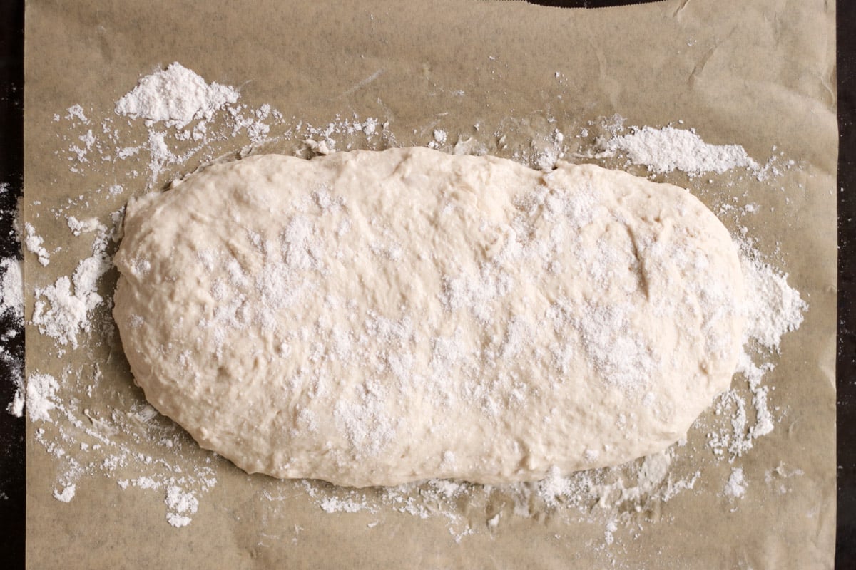 close up image of ciabatta dough on a parchment lined sheet.