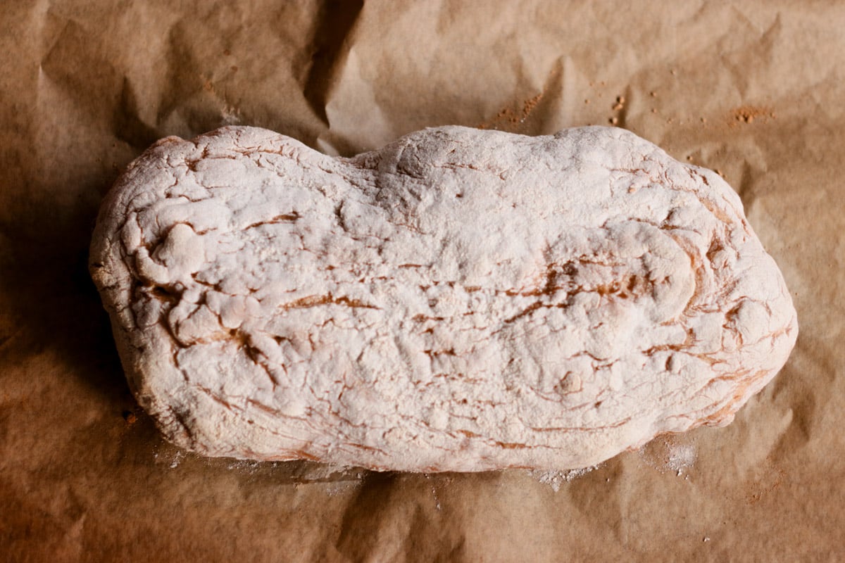 closeup image of ciabatta bread on a parchment lined baking sheet.