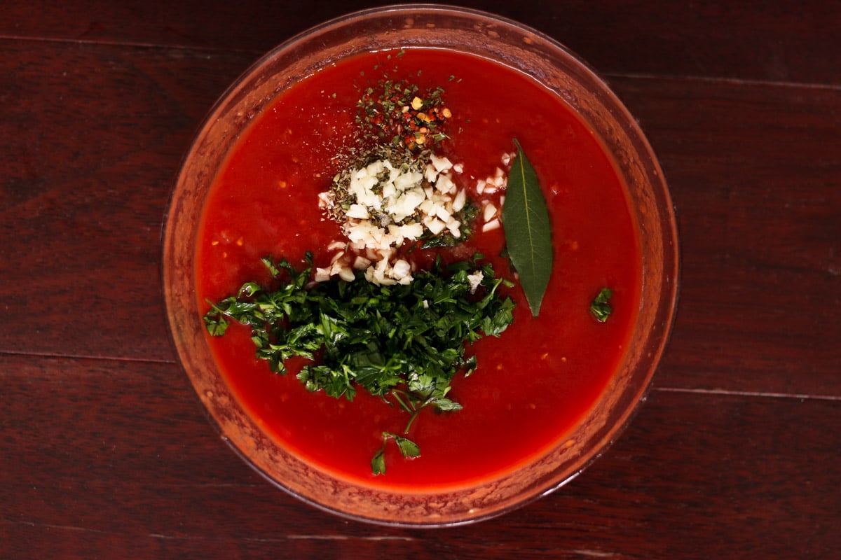 close up image of making San Marzanano pizza sauce in a glass bowl.