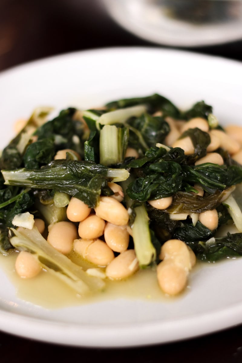 close up image of greens and beans in a white plate.