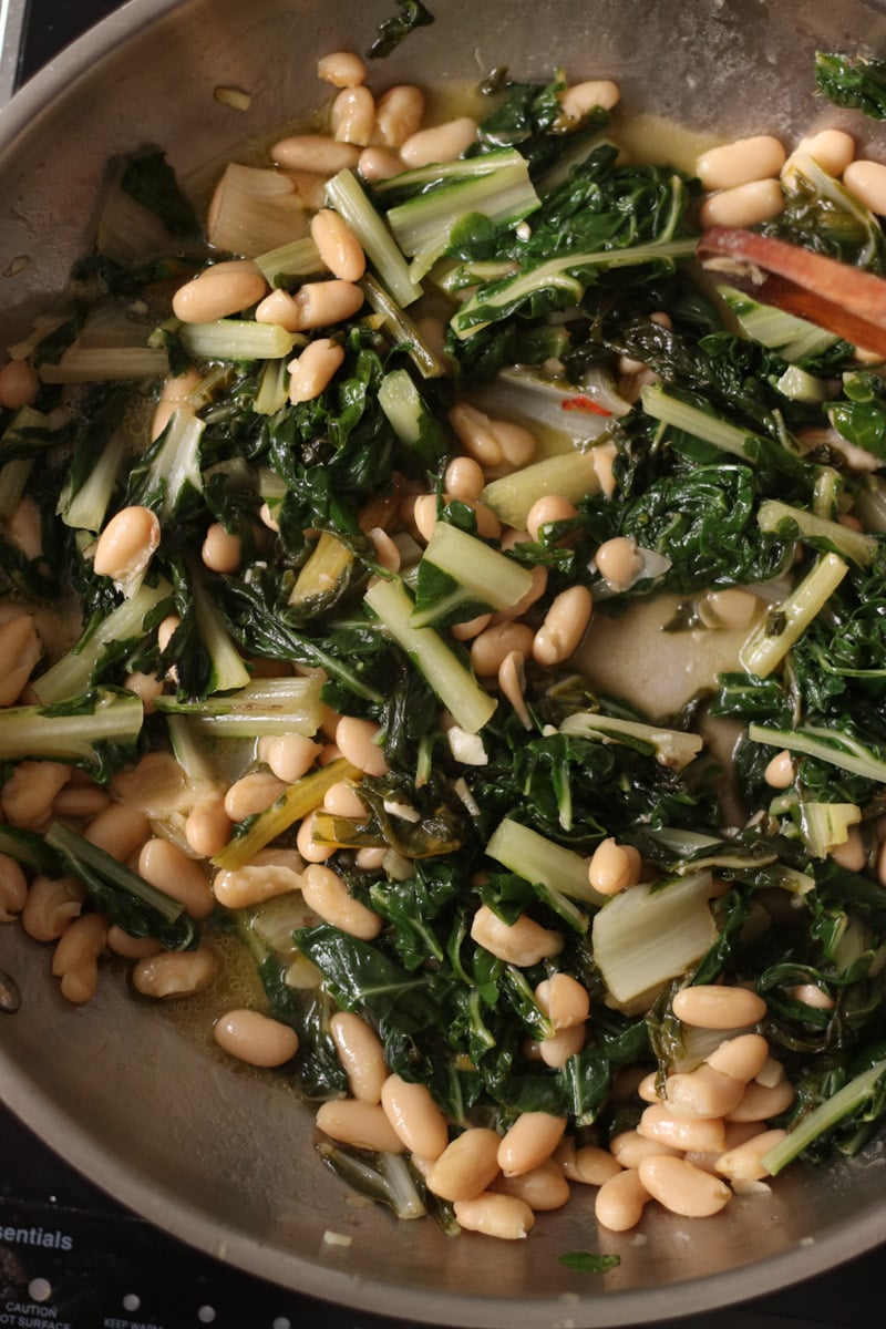 close up image of chard and beans in a skillet.