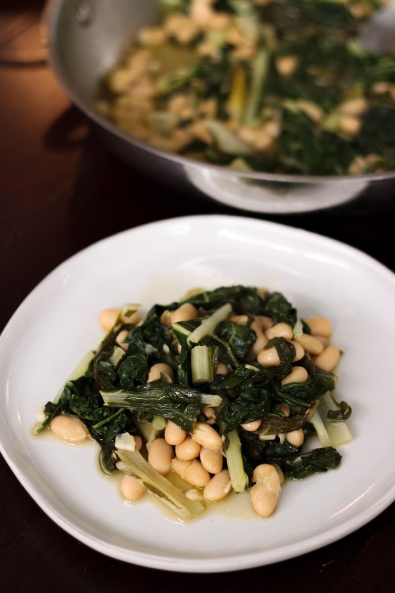 close up image of greens and beans on a white plate.