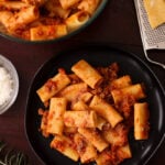 Rigatoni bolognese on a black dish.