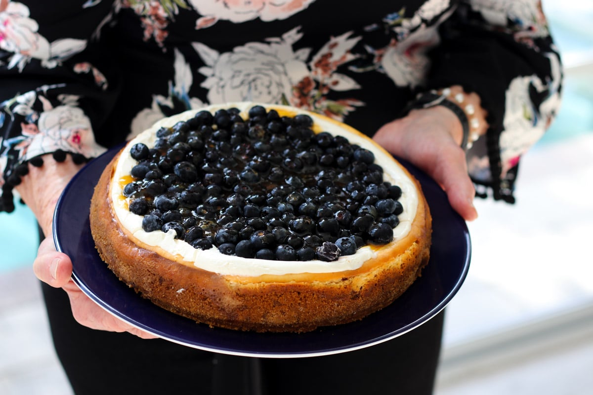 close up image of lady holding a cheesecake.