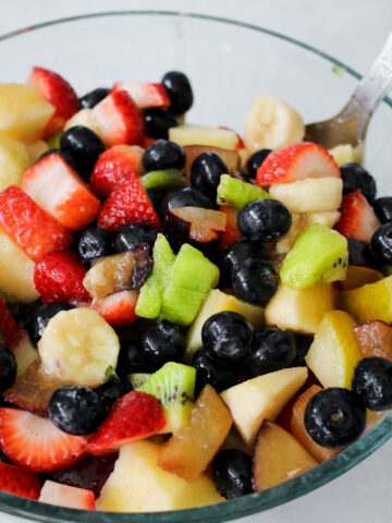 "Close-up of vibrant Macedonia di Frutta showcasing chopped apples, kiwis, plums, strawberries, and blueberries.