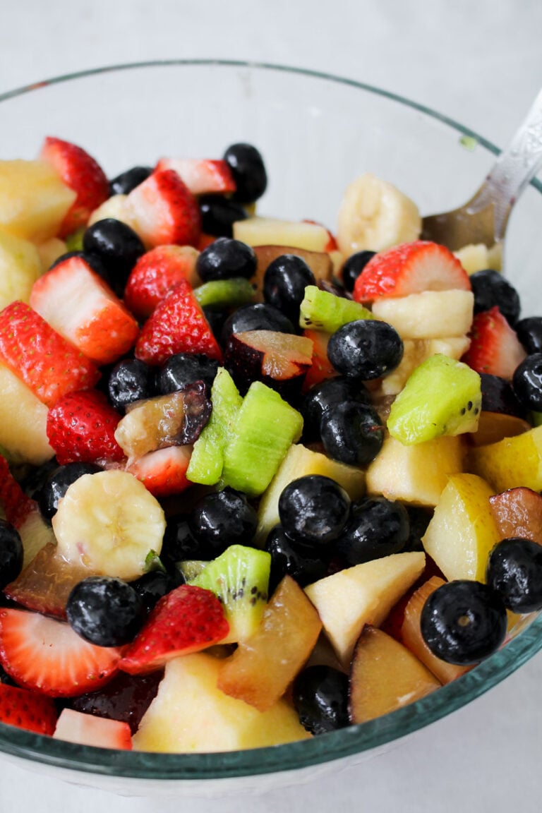 "Close-up of vibrant Macedonia di Frutta showcasing chopped apples, kiwis, plums, strawberries, and blueberries.