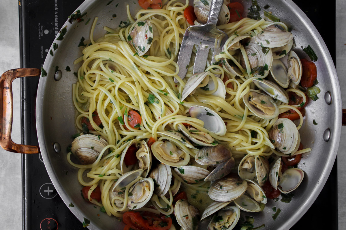 overhead image of making pasta and clams in a large skillet. 