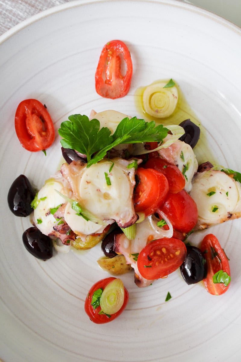 overhead image of grilled octopus salad on a white plate.