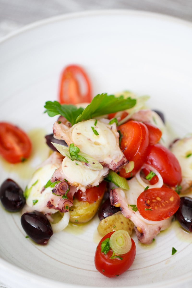 close up image of octopus salad on a white plate.