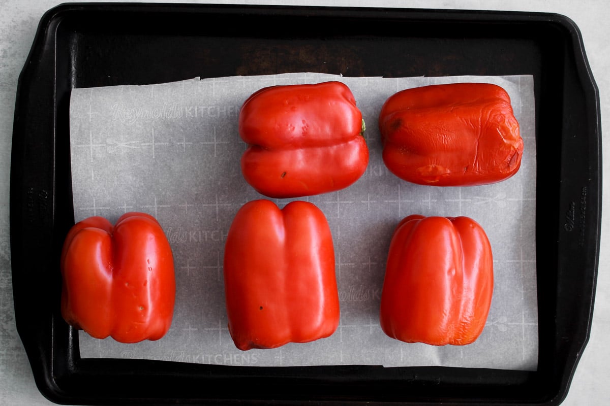 overhead image of red peppers on a parchment lined baking sheet.