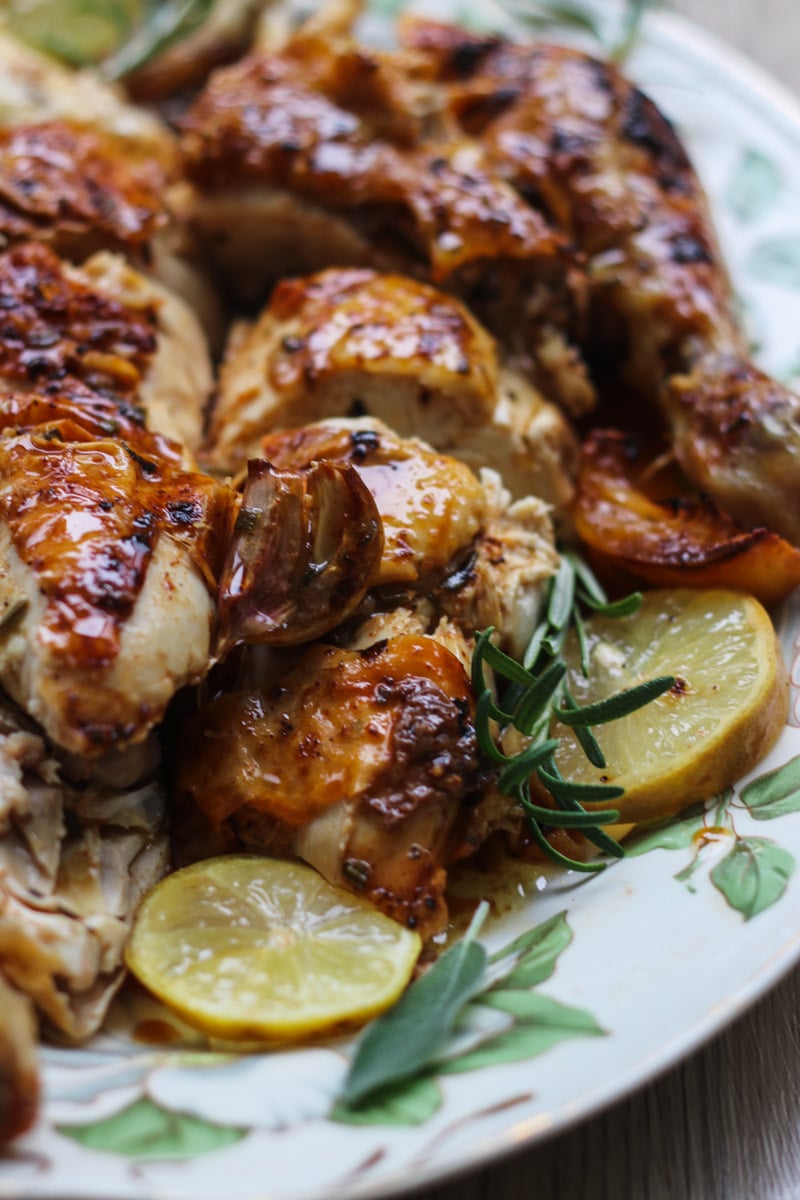 close up image of whole roasted chicken with lemon and rosemary.