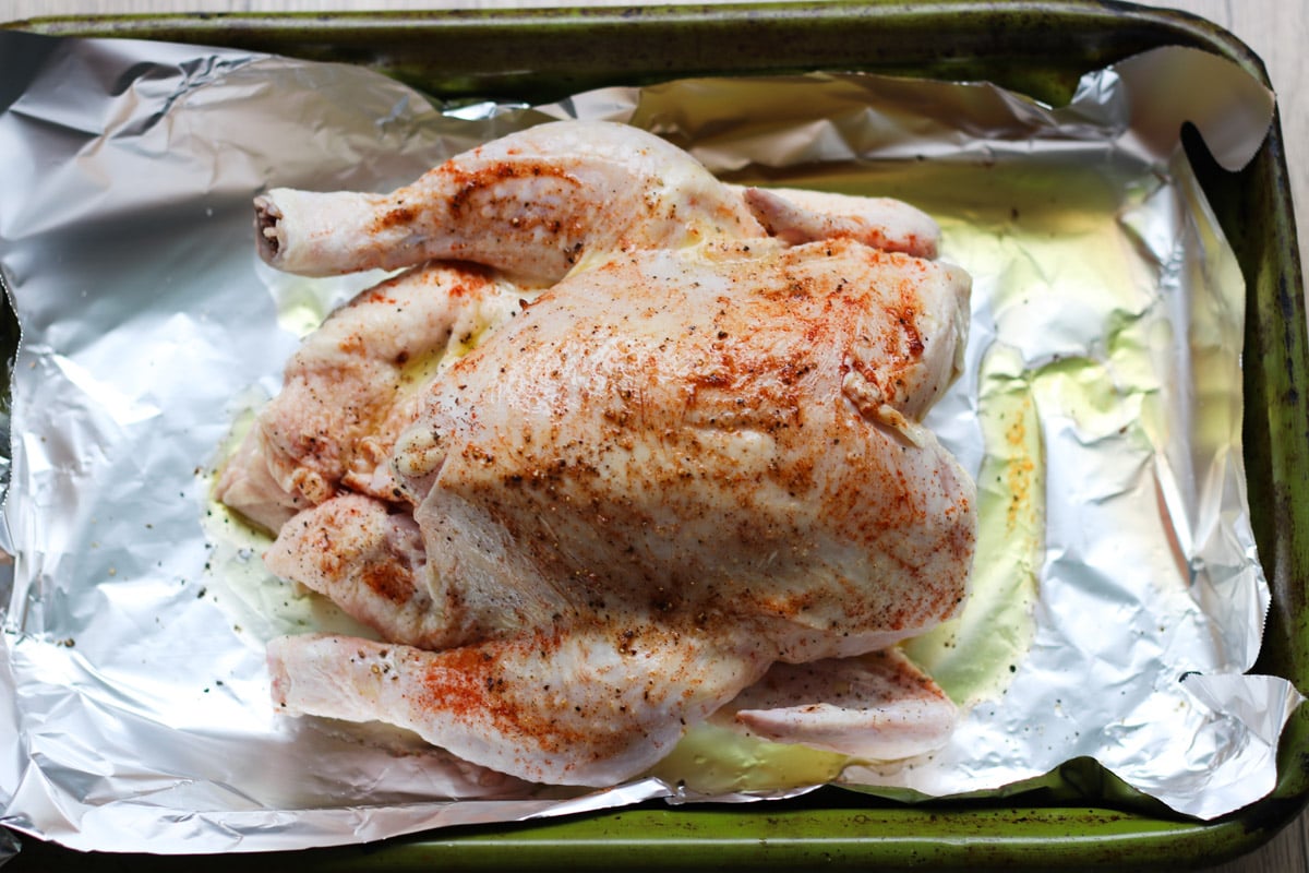 overhead image of a whole chicken on a roasting tray.