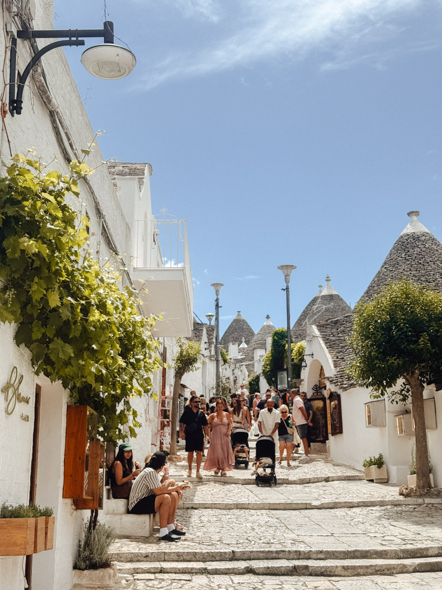 Panoramic view of Alberobello, Puglia, with whitewashed trulli houses and conical stone roofs under a blue sky