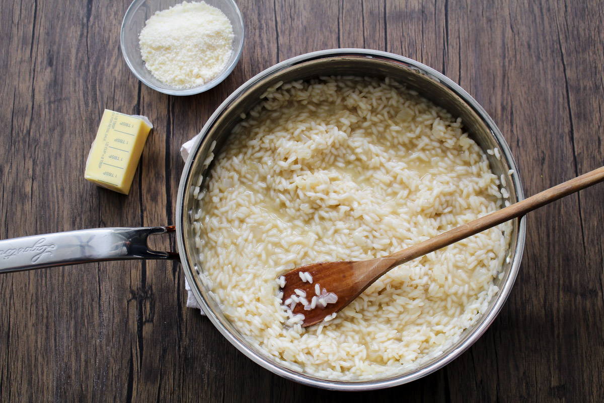 overhead image of making lemon risotto in a skillet and a wooden background.