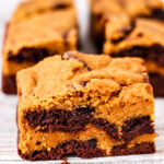 A square pumpkin brownie-cookie swirl bar with layers of golden cookie dough and dark chocolate brownie.