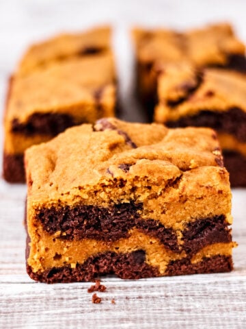 A square pumpkin brownie-cookie swirl bar with layers of golden cookie dough and dark chocolate brownie.