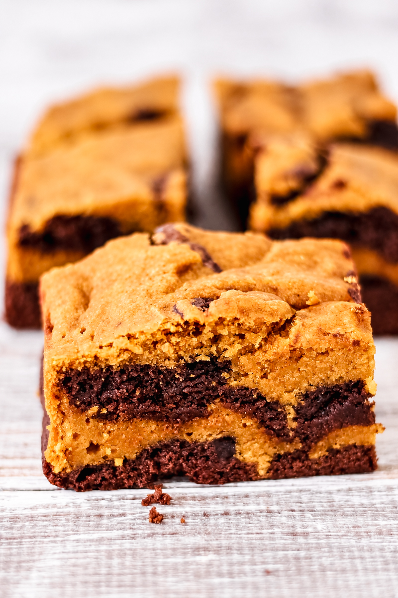 A square pumpkin brownie-cookie swirl bar with layers of golden cookie dough and dark chocolate brownie.