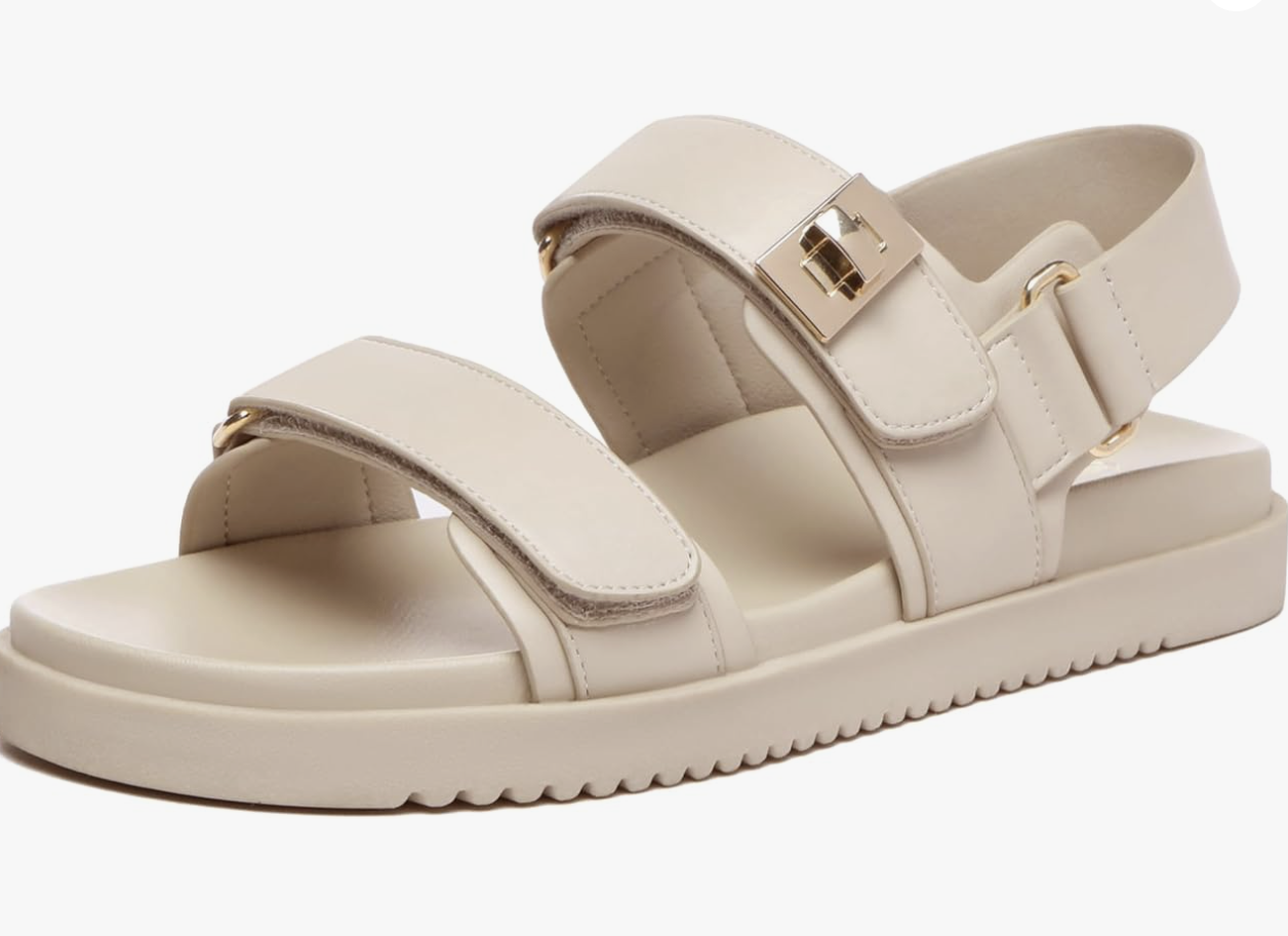 A beige sandal with two front straps and an ankle strap, all featuring gold buckles. With its thick, textured sole and minimalist design, it's a chic choice for what to wear in Italy during your stylish travels.