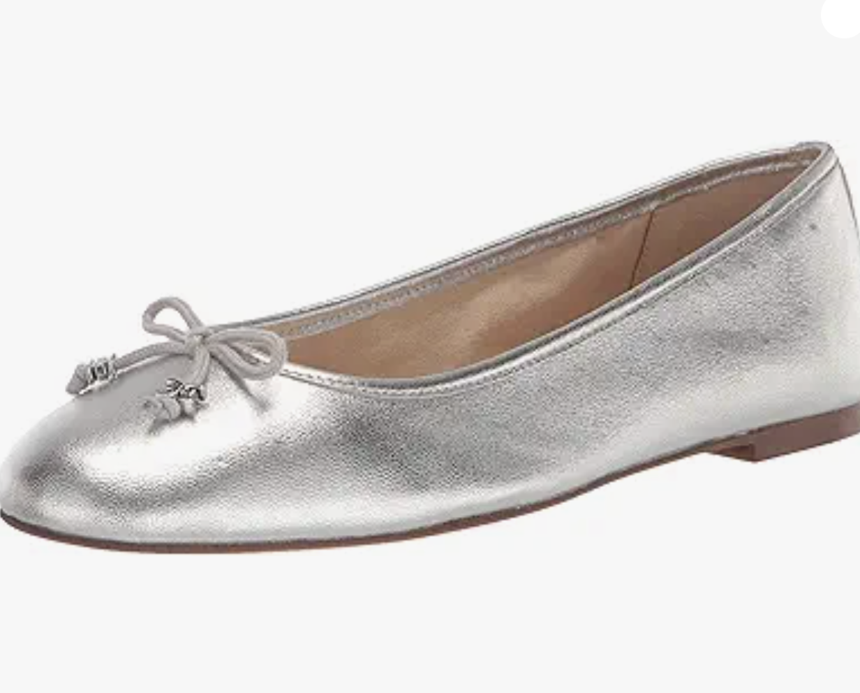 A silver ballet flat shoe with a small bow and metallic charms on the toe, featuring a low heel and rounded toe-perfect for stylish comfort if you're wondering what to wear in Italy.