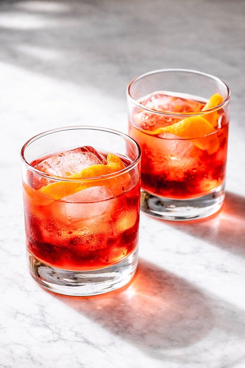 Two glasses of red liquid with orange slices and ice, negroni.