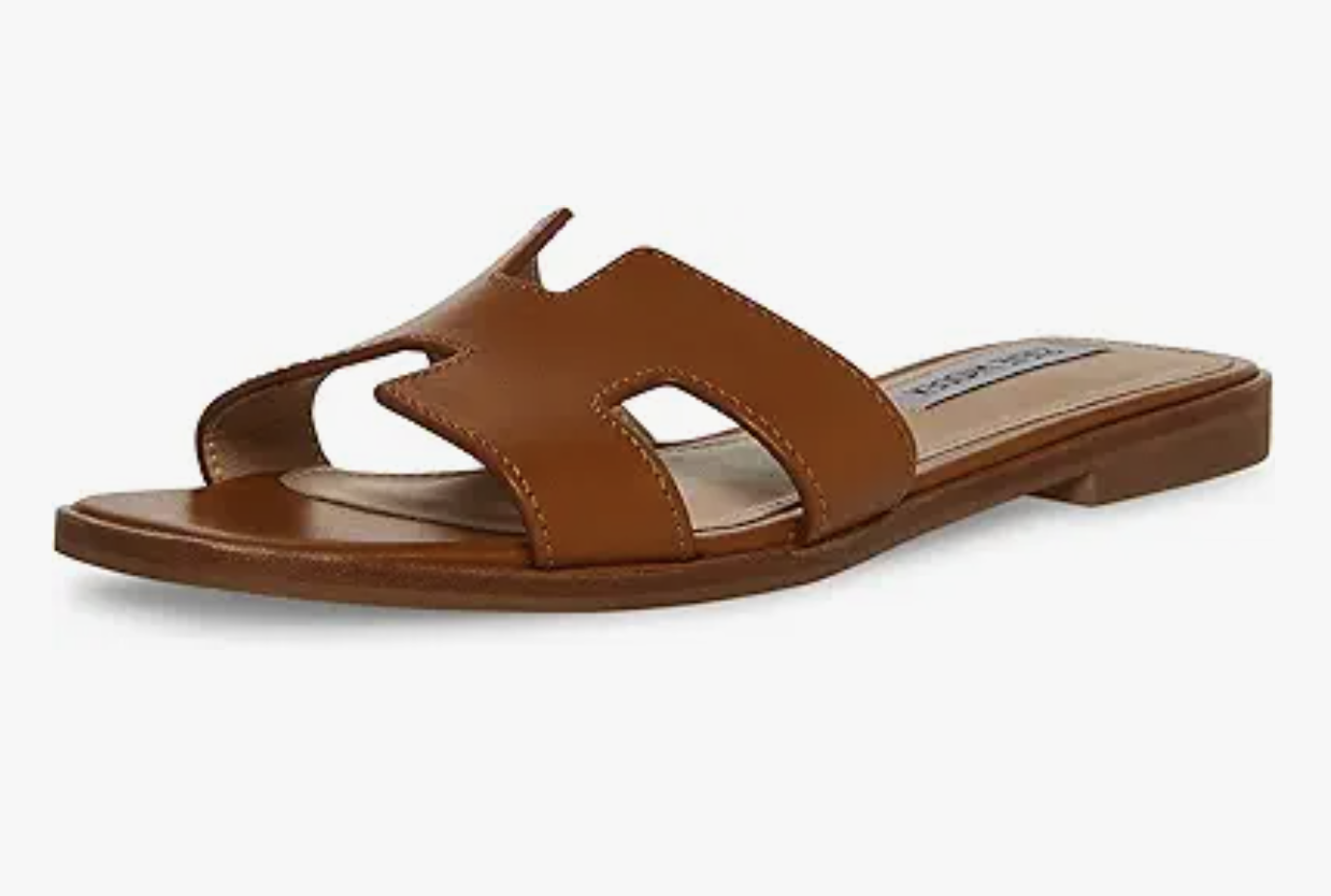 A brown flat slide sandal with an open toe and a cutout design on the strap, displayed at an angle on a white background-perfect for those wondering what to wear in Italy for effortless style and comfort.