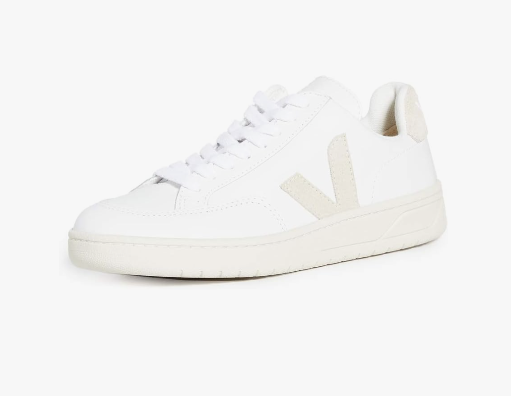 A white low-top sneaker with a beige V logo on the side, white laces, and a white sole-perfect for those wondering what to wear in Italy-photographed against a plain white background.